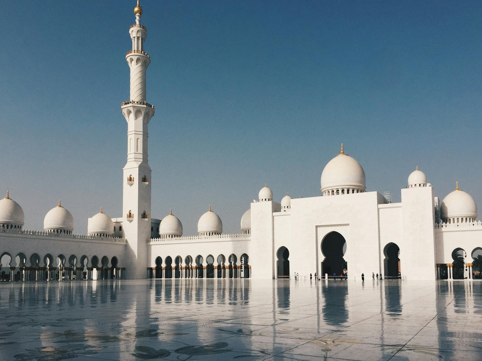 Beautiful view of Sheikh Zayed Grand Mosque with minarets and domes in Abu Dhabi under a clear blue sky.